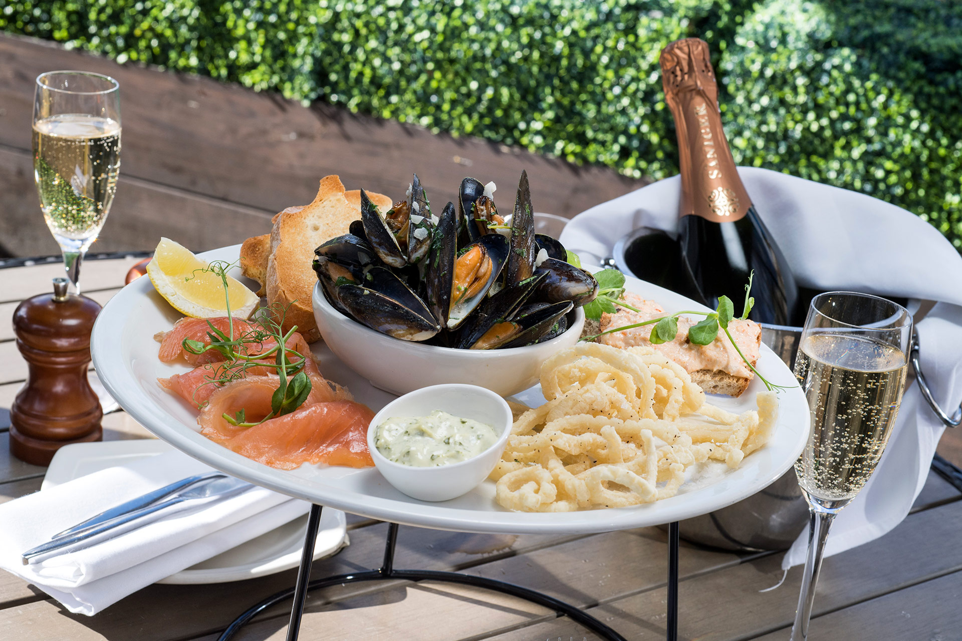 Photograph of An assortment of seafood served with champagne on a large platter in the sunshine. by Manchester photography book for food & drink